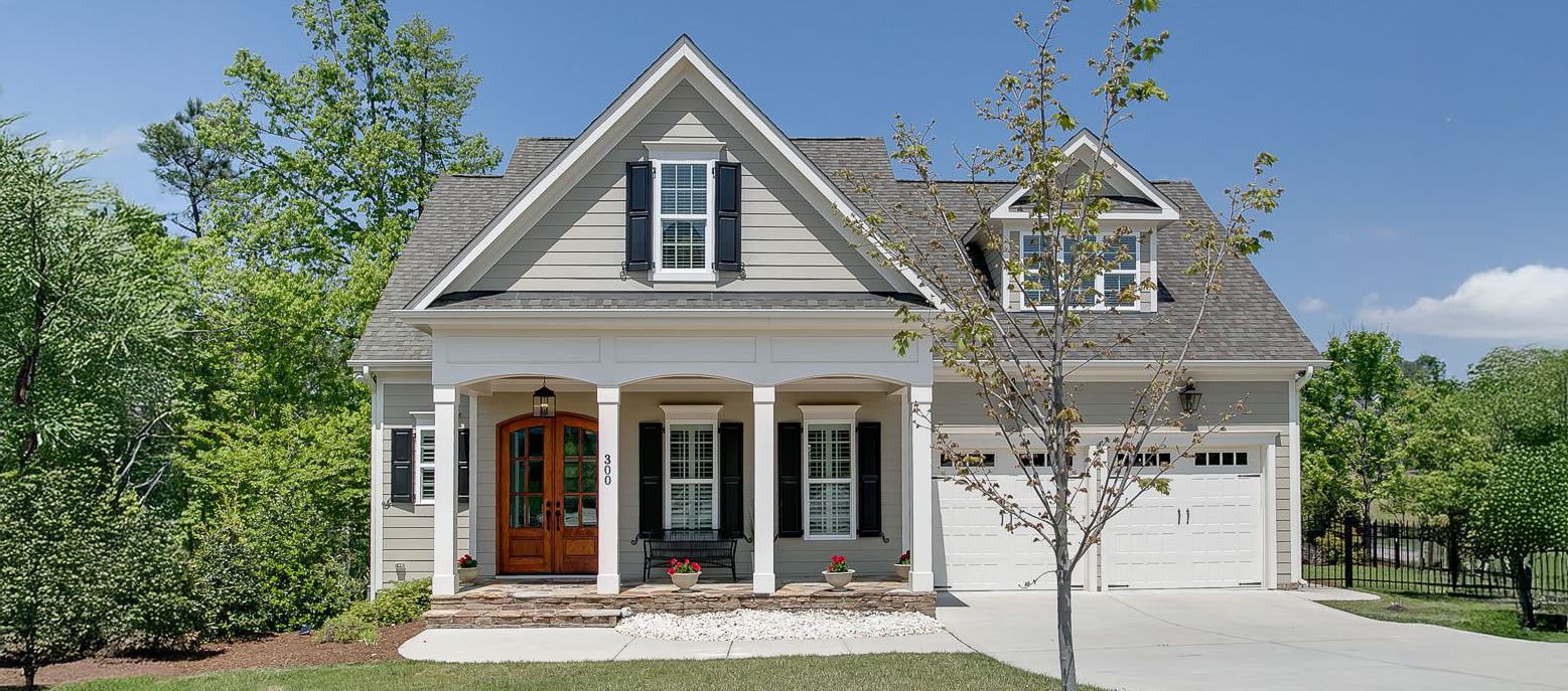 Charming craftsman-style home in Cary, featuring a welcoming front porch, elegant wood door, and beautifully landscaped yard.